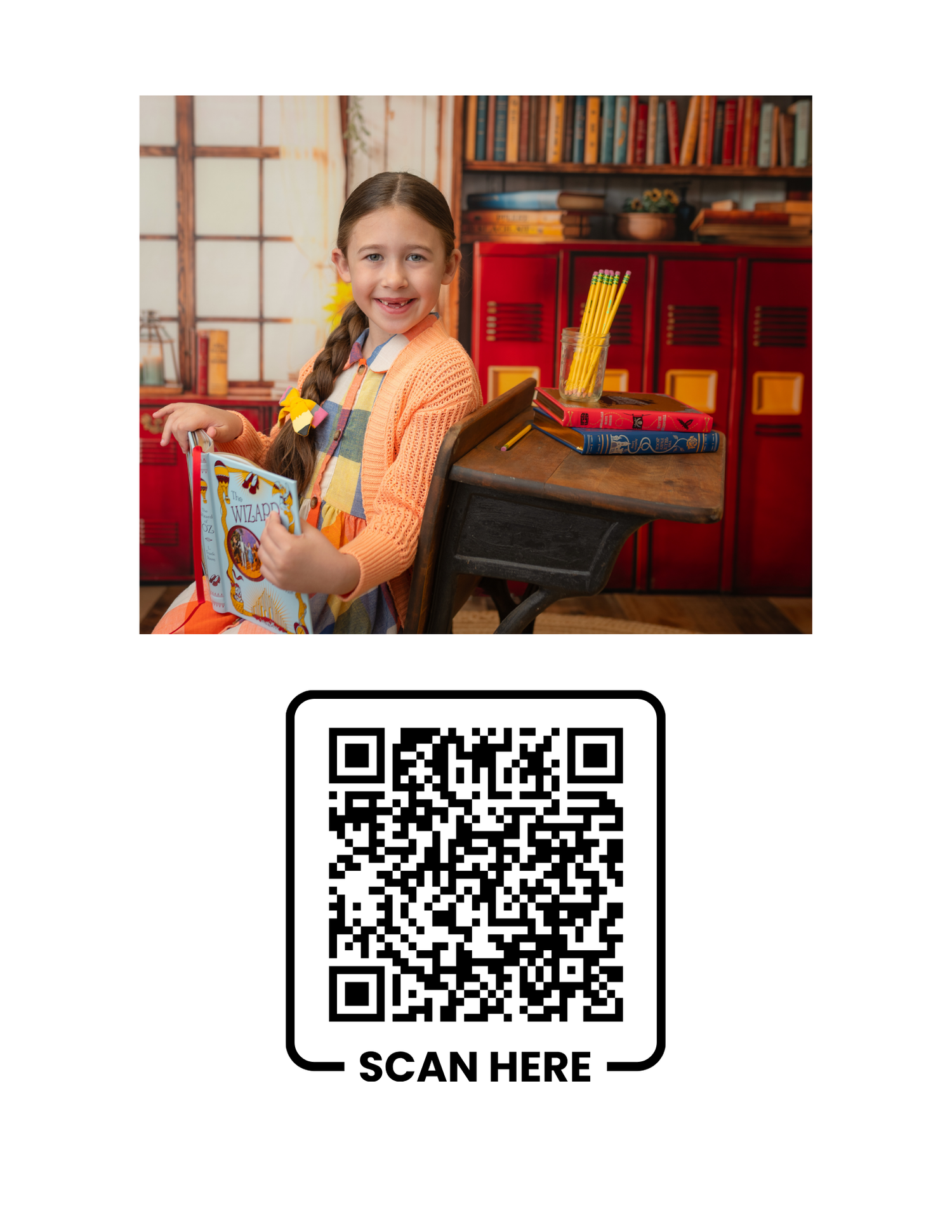 A smiling girl holds a colorful book at a vintage desk, surrounded by books and a red cabinet.