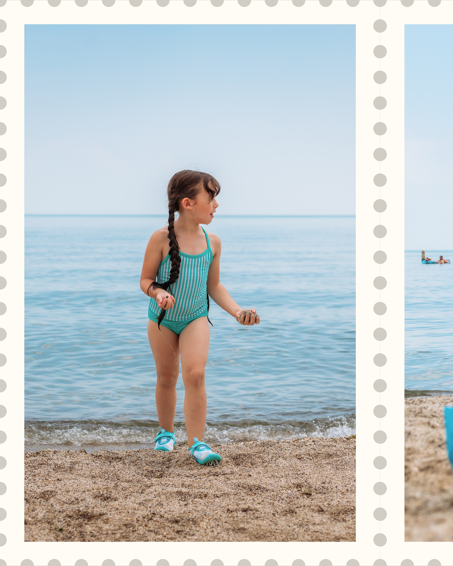 A small figure stands on the beach in a turquoise swimsuit and water shoes beside the calm blue ocean.