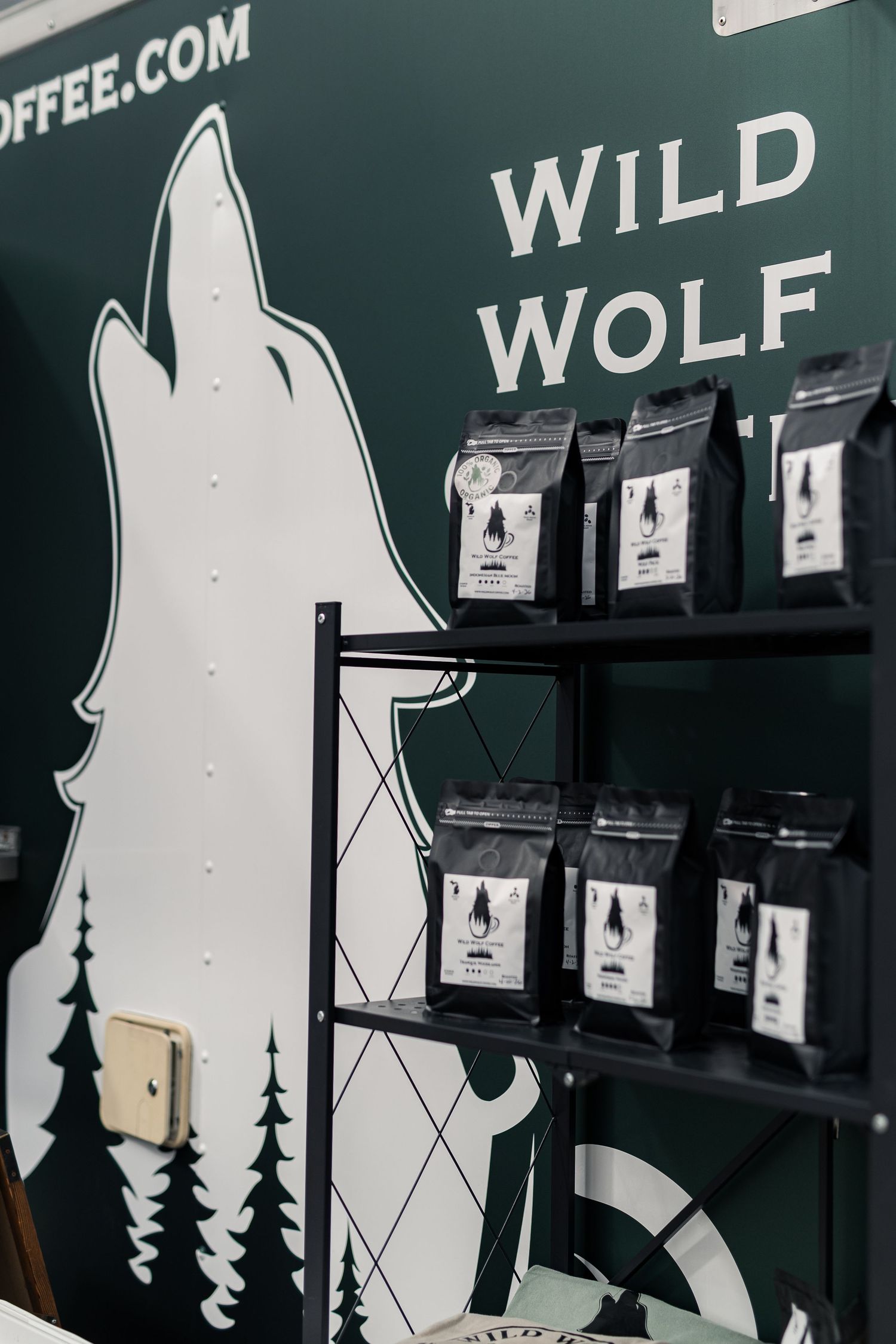 Wild Wolf Coffee branded wall display with black packaged coffee bags on metal shelving.