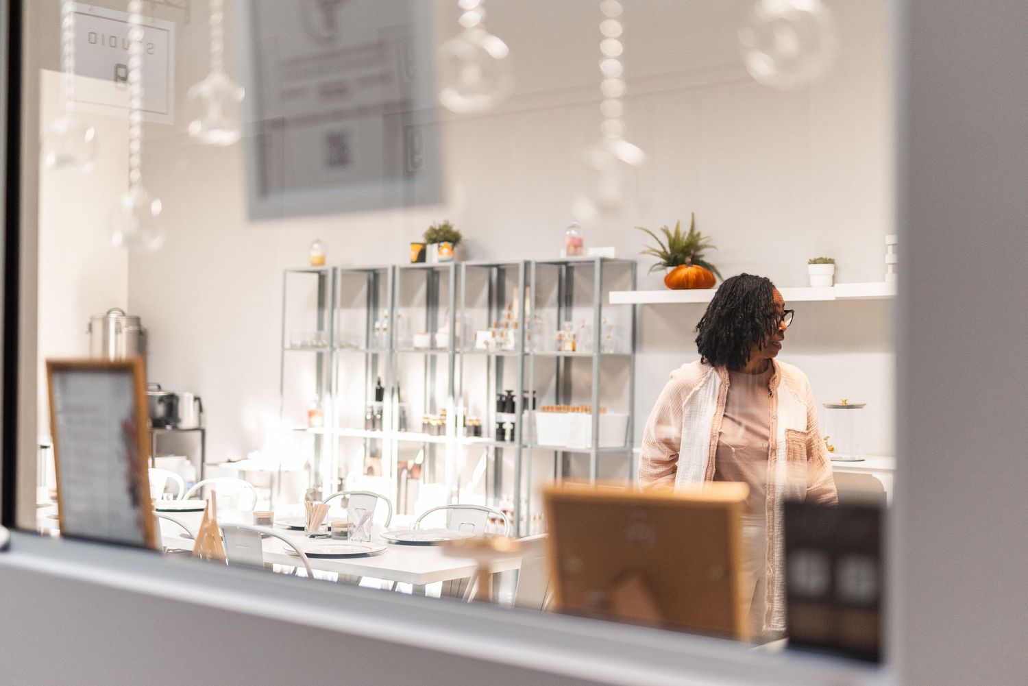 Woman working behind counter in bright modern retail shop with elegant pendant lights.