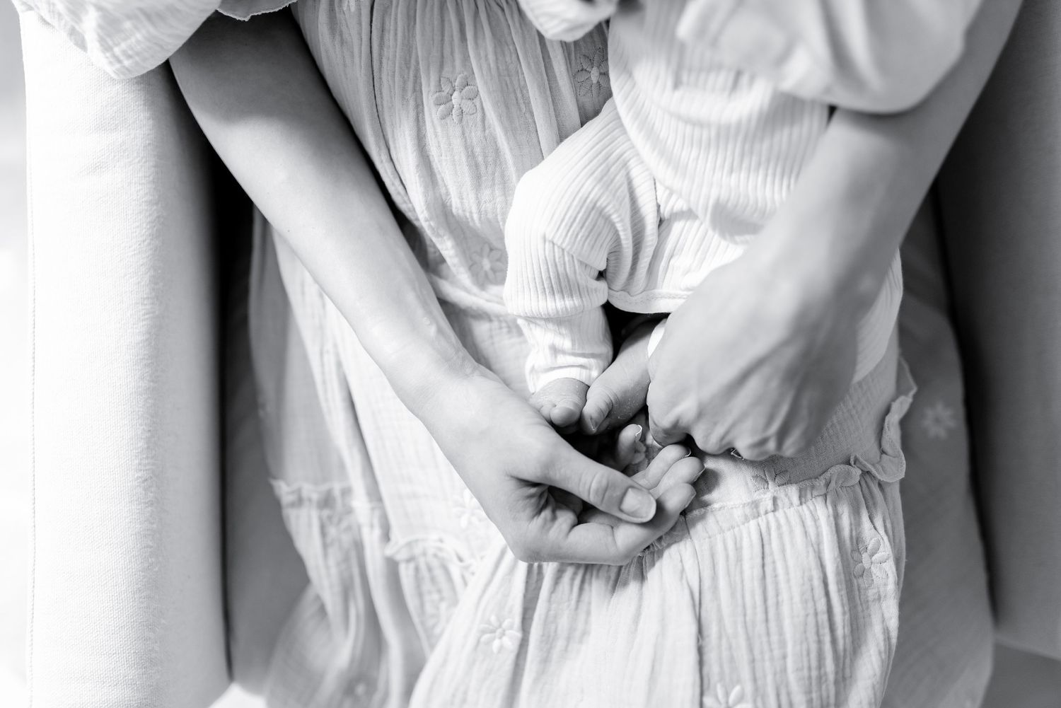 A close-up black and white shot of someone's hands grasping the fabric of a white dress or garment.