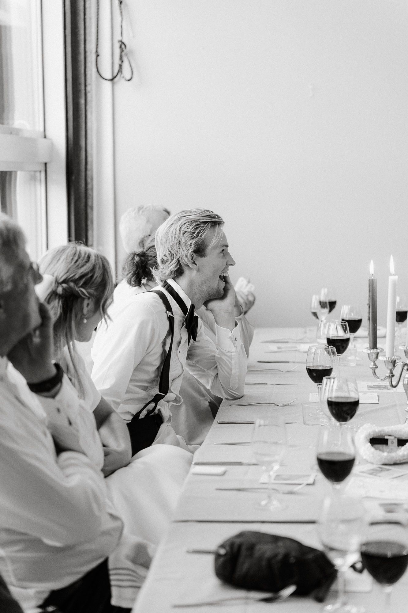 A black and white series of candid wedding reception photos showing guests seated at an elegant dinner table.