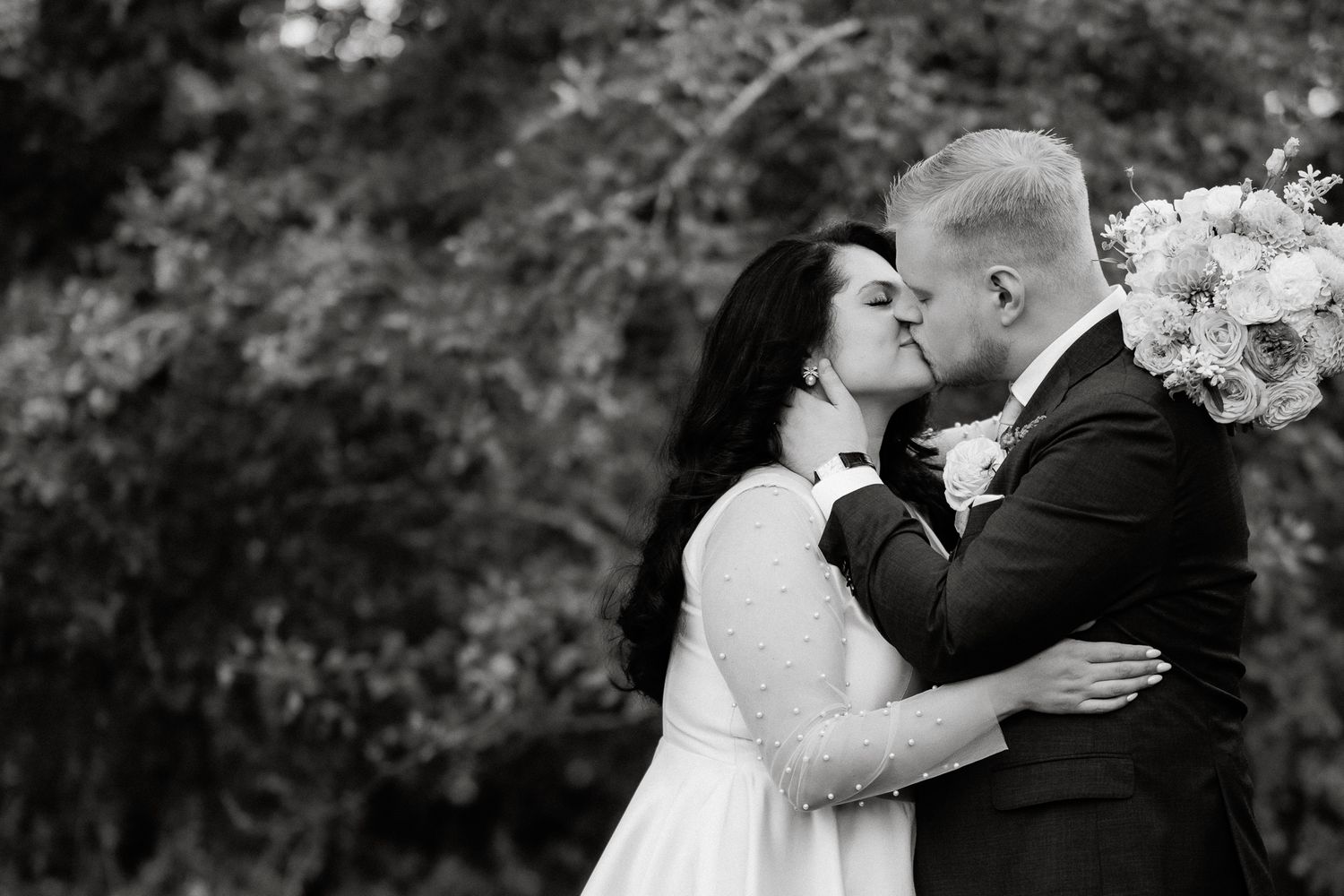 A romantic wedding couple shares intimate kisses in a series of black and white photographs in an outdoor setting.
