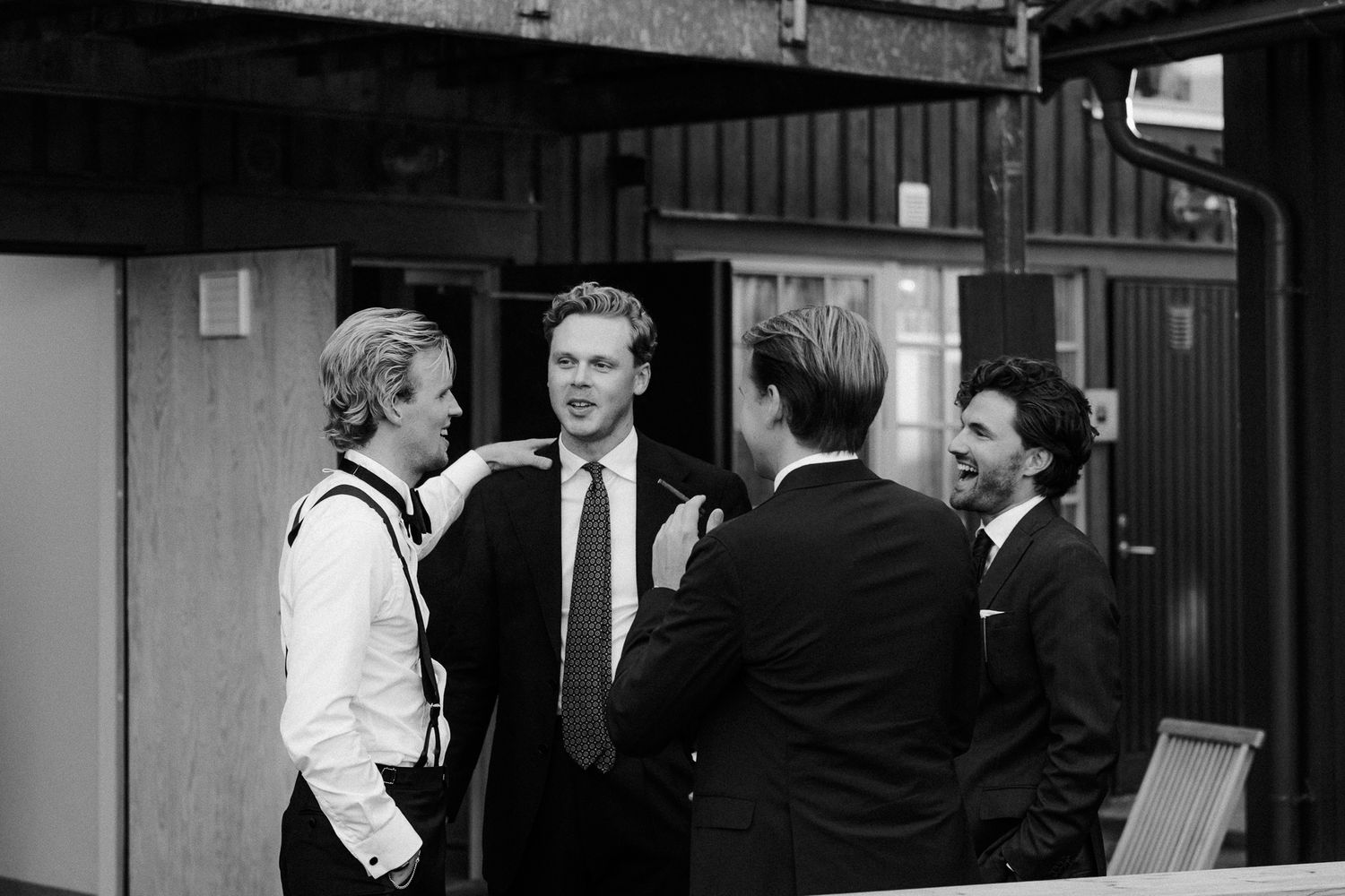 A black and white vintage photograph shows people gathered and laughing in what appears to be a social setting.