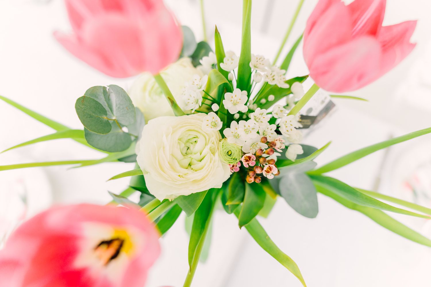 Close up of pink tulips and white ranunculus flowers in a delicate spring arrangement.