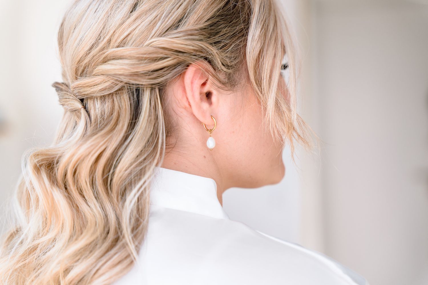 Elegant blonde updo hairstyle shown from multiple angles with pearl earrings and white top.