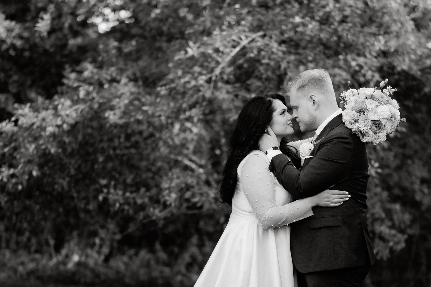 A romantic outdoor wedding ceremony shows a couple embracing in a lush garden setting.