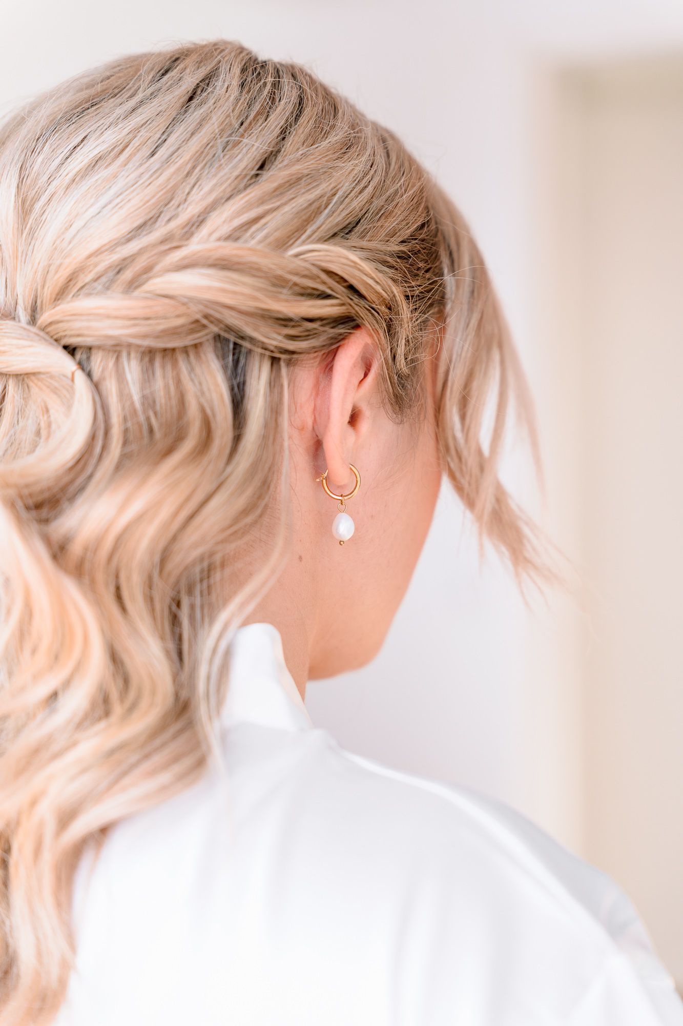Close up view of delicate ear piercings with minimalist jewelry on blonde hair.