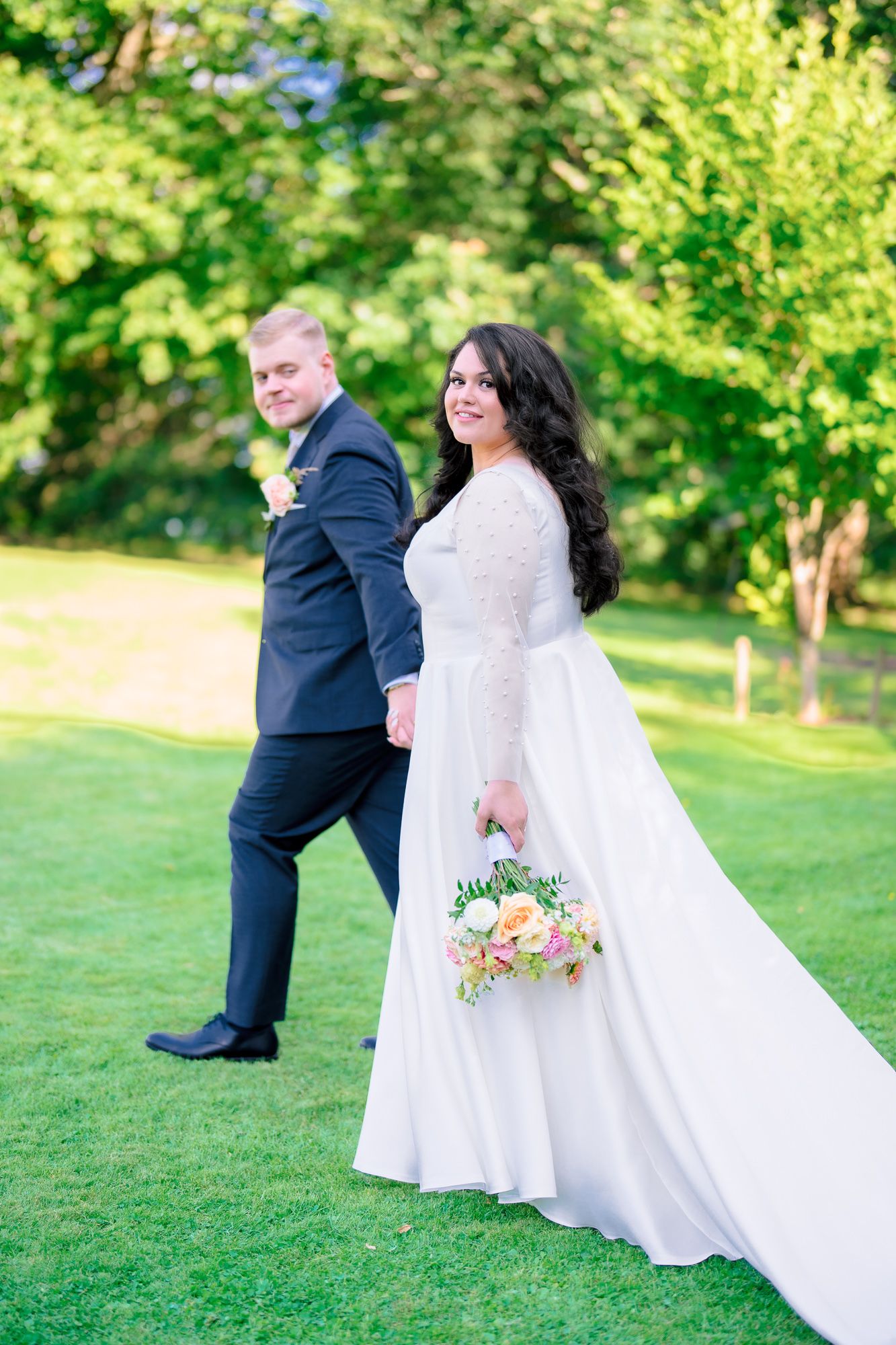 Wedding couple shares romantic moment on green lawn as bride dips back in elegant white gown at outdoor ceremony.