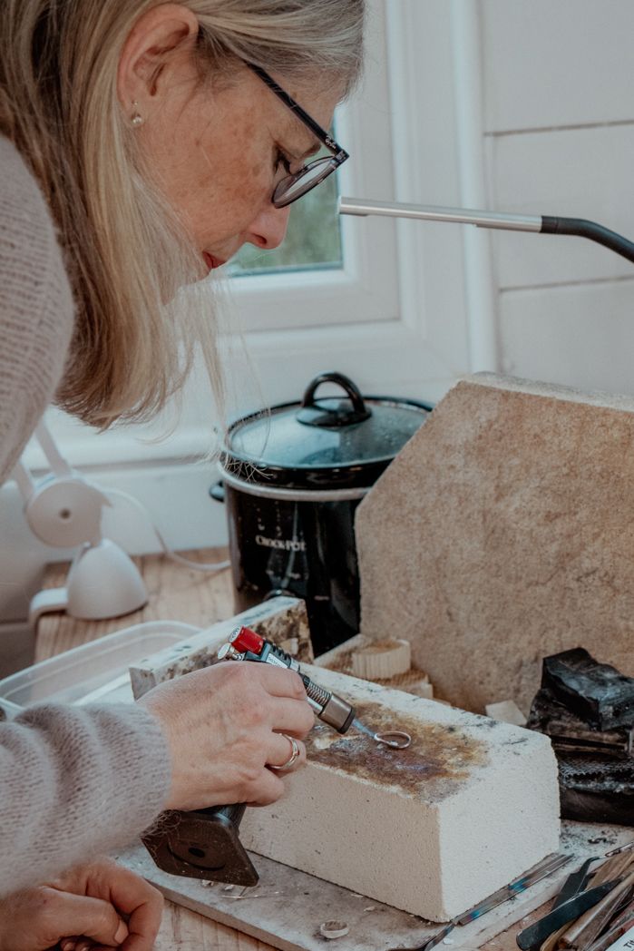 Detailed jewellery work being performed on a white surface with tools and equipment.