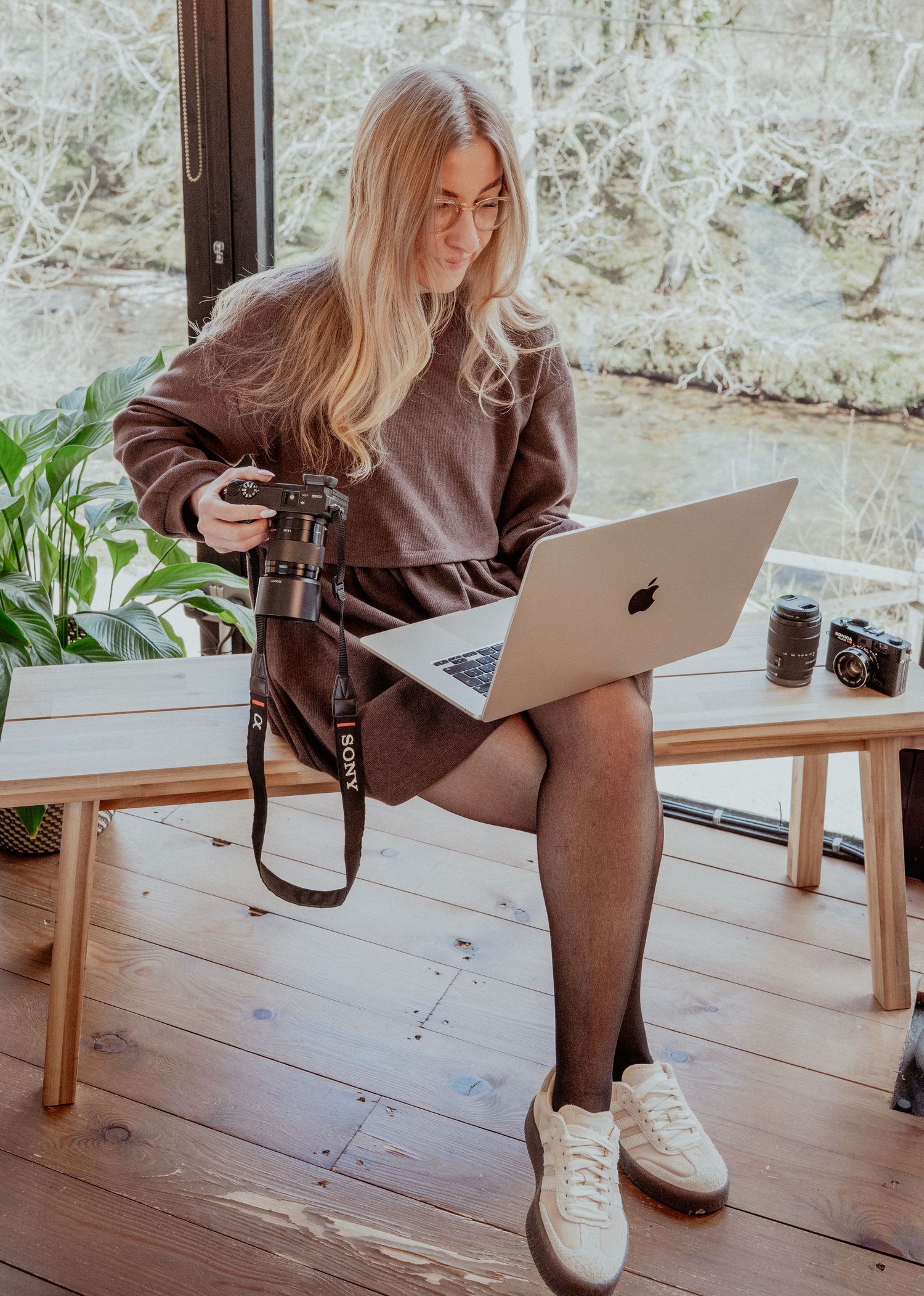 A photographer works with camera equipment and laptop in a bright wooden interior space.
