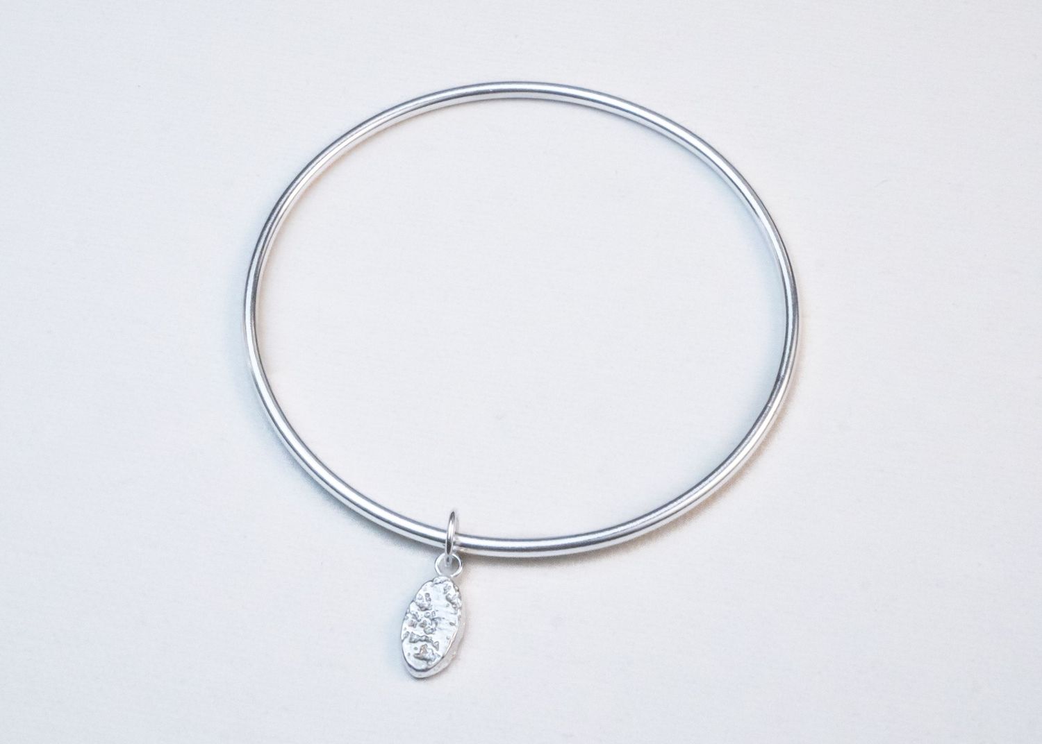 Four sterling silver bangle bracelets displayed on a white background showing different angles and styles.