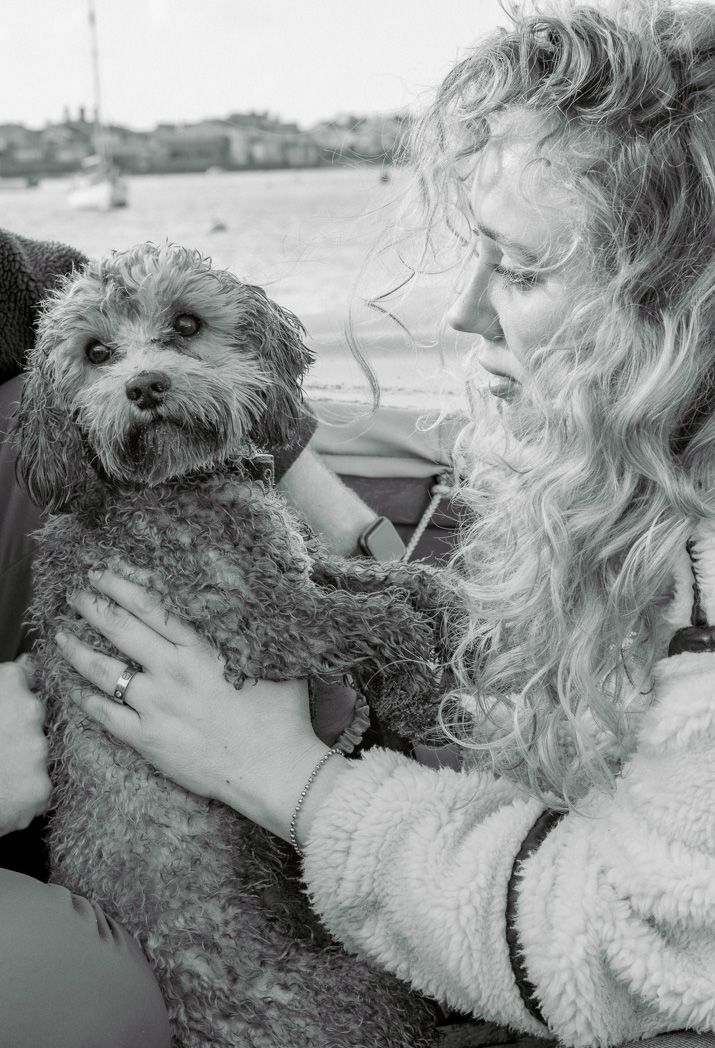 Black and white portrait of a person holding a scruffy terrier dog in a cozy embrace.
