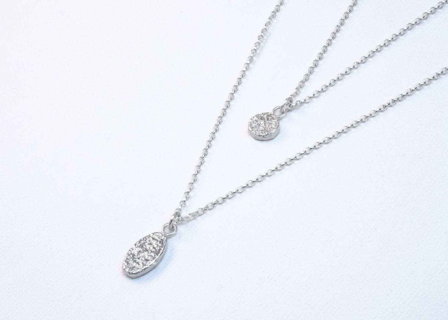 Delicate silver pendant necklaces with cubic zirconia crystals displayed on white background.