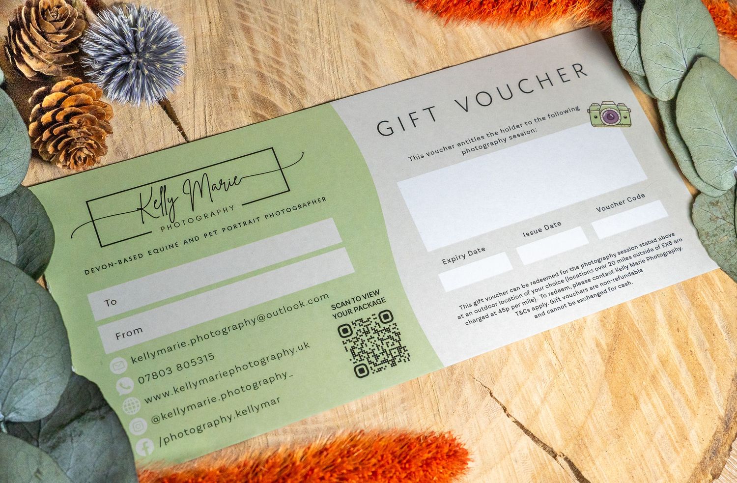 Gift voucher or certificate shown with decorative pine cones, eucalyptus leaves and orange accents on beige fabric.
