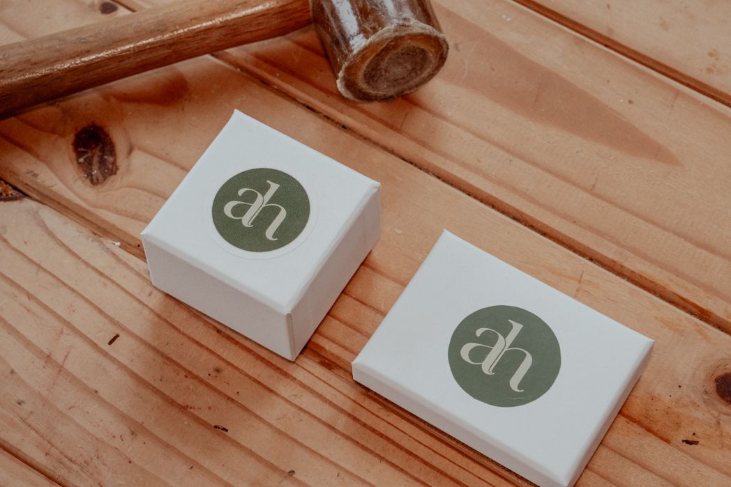 Two white square boxes with green circular logo designs on wooden surface.