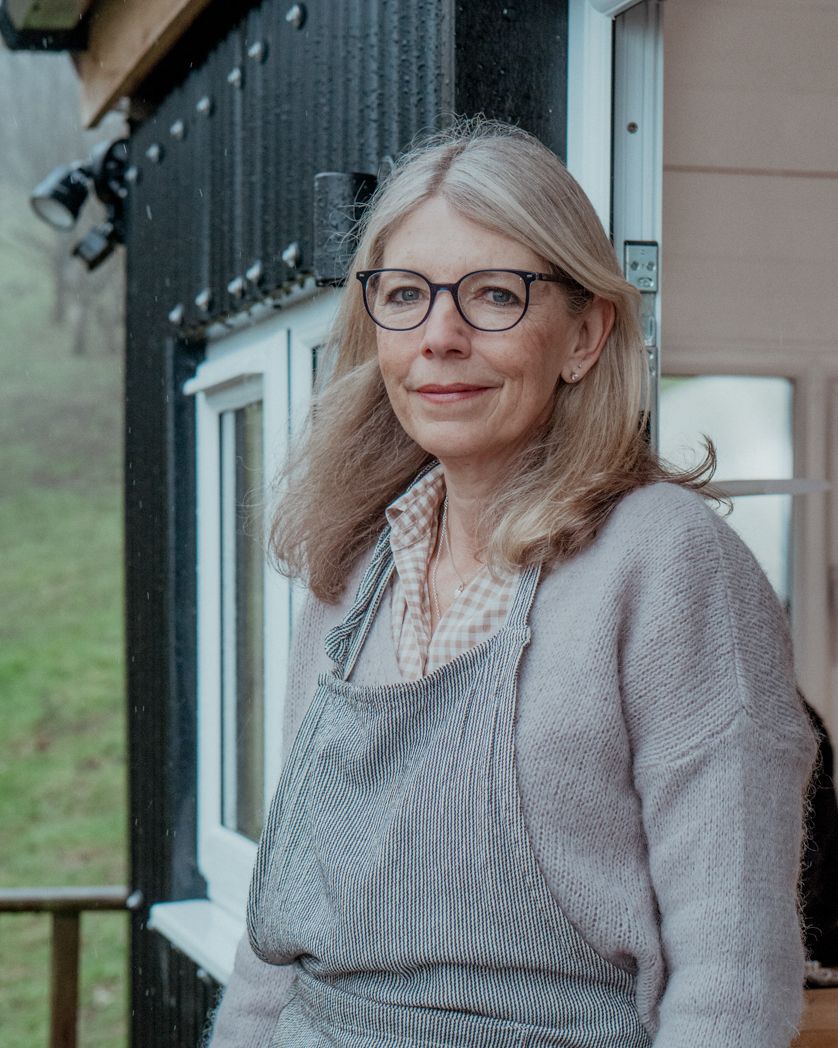 An artisan working in their studio wearing grey clothing on a covered porch.