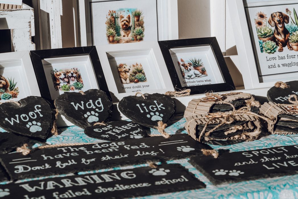 Display of framed pet-themed artwork and merchandise on wooden surface.