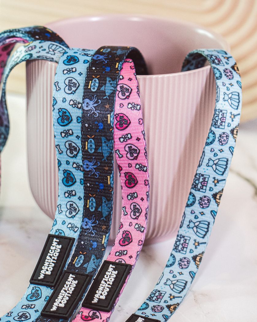 Assorted pet leads in blue and pink patterns with repeating designs displayed on pink surface.