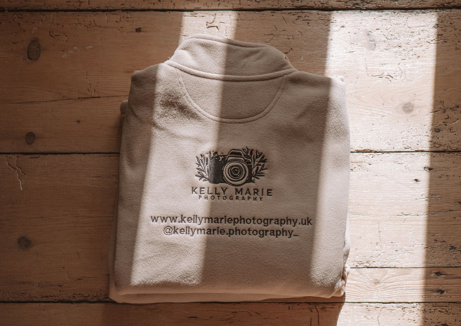 Folded white t-shirt with photography business logo and website printed on the back.