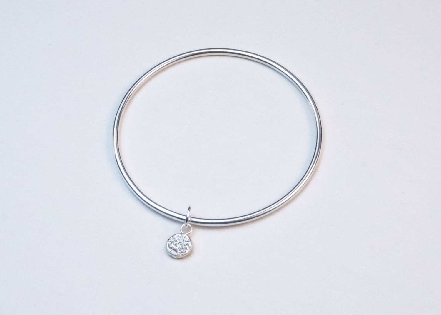 Silver bracelet shown in multiple stages of closure, demonstrating how the bangle clasp works.