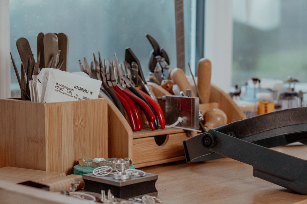 Wooden organizer filled with jewelry making tools and supplies on a workbench.