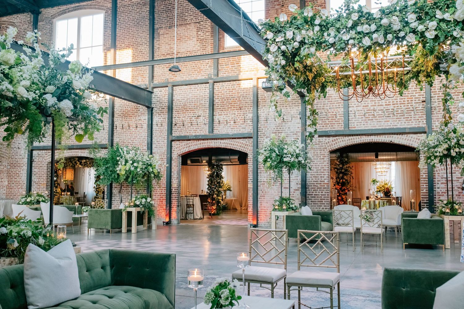 Industrial brick venue decorated with hanging greenery and string lights for wedding reception.