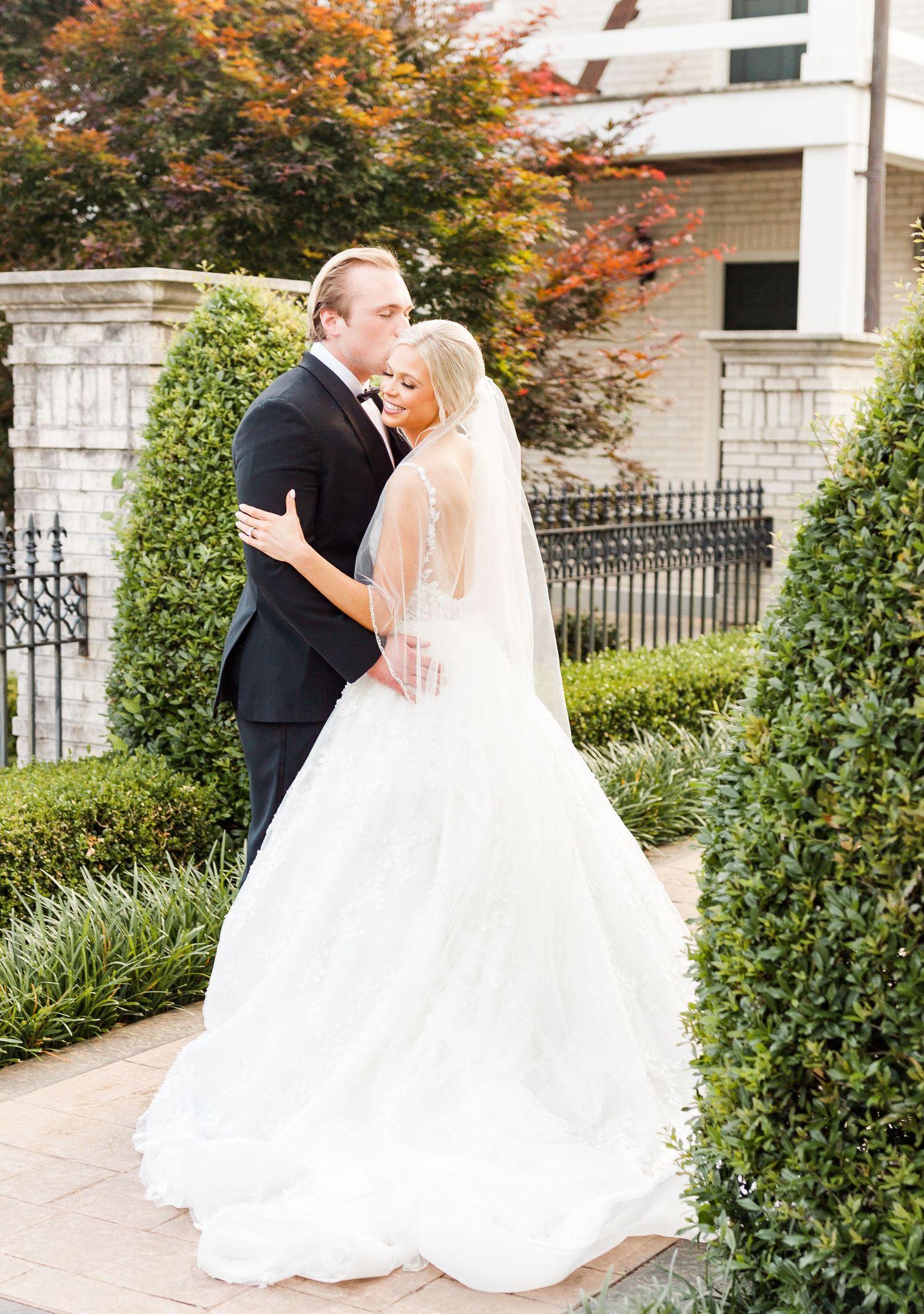 Couple shares romantic moments among autumn foliage and garden architecture.