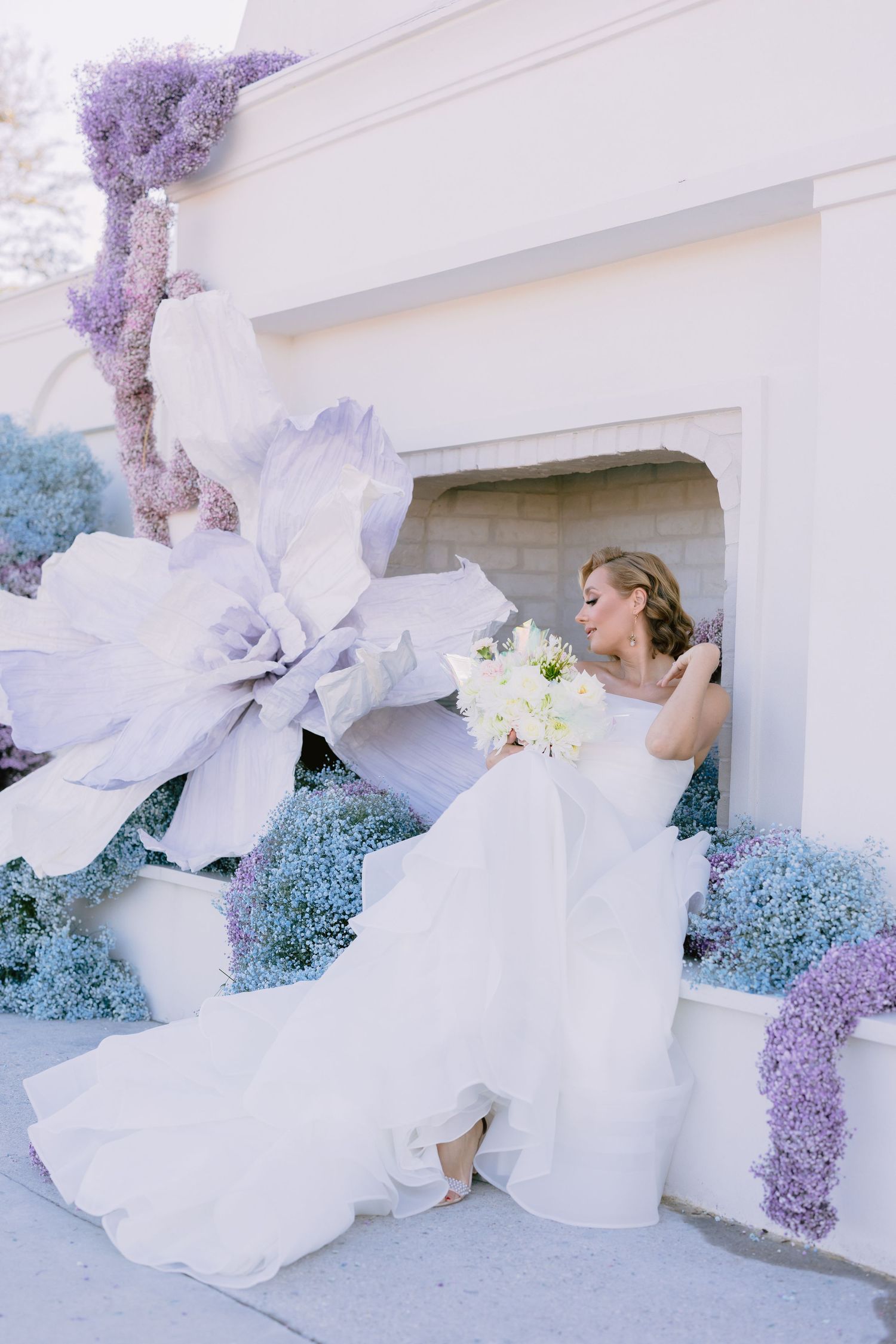 Dramatic bridal portraits with flowing white dress against purple wisteria and architectural details.