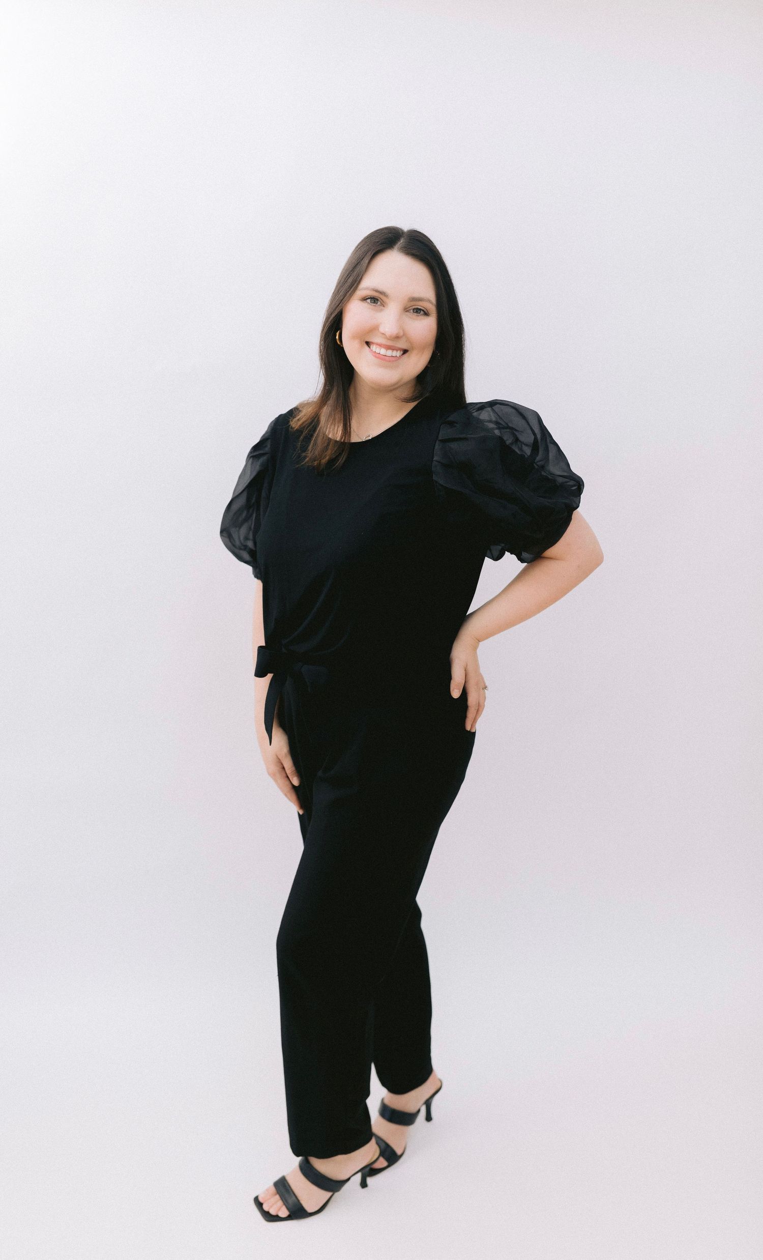 A person in a black outfit poses playfully in four different positions against a light grey backdrop.
