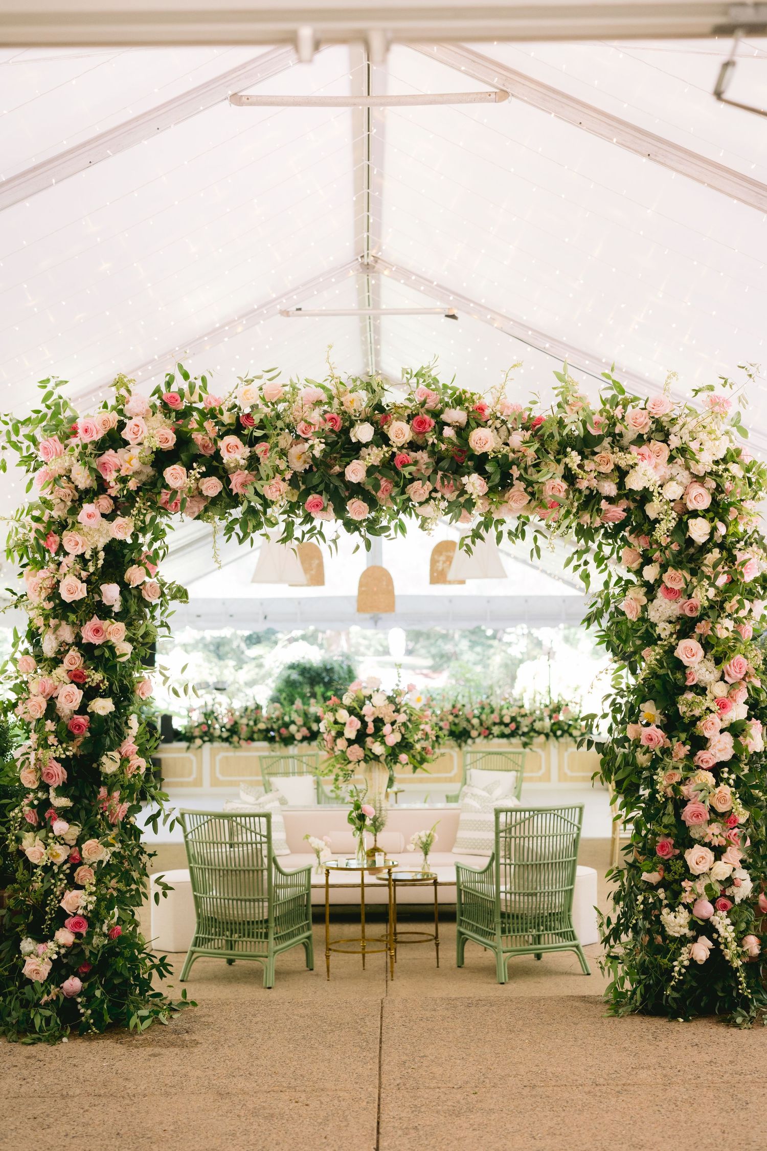 Romantic wedding tent decorated with lush pink roses and greenery creating an enchanting floral canopy.