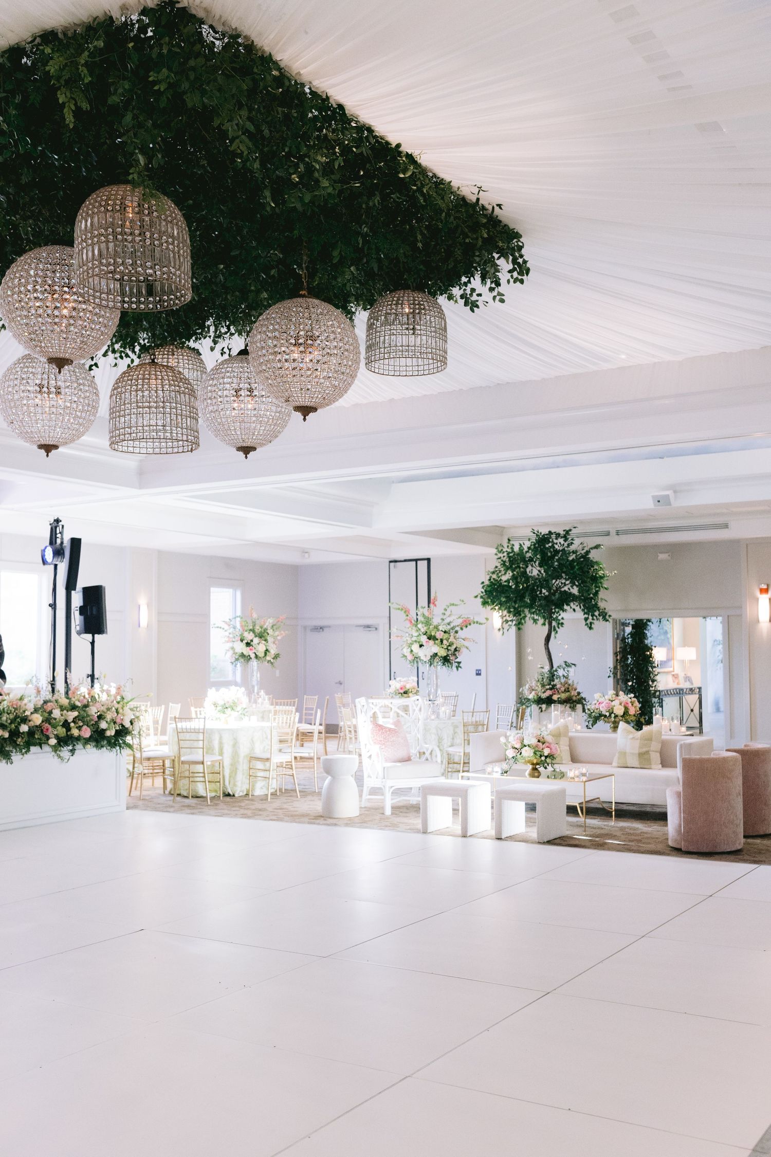 Elegant white reception hall decorated with crystal chandeliers and greenery for a wedding celebration at the Memphis Botanical Gardens.