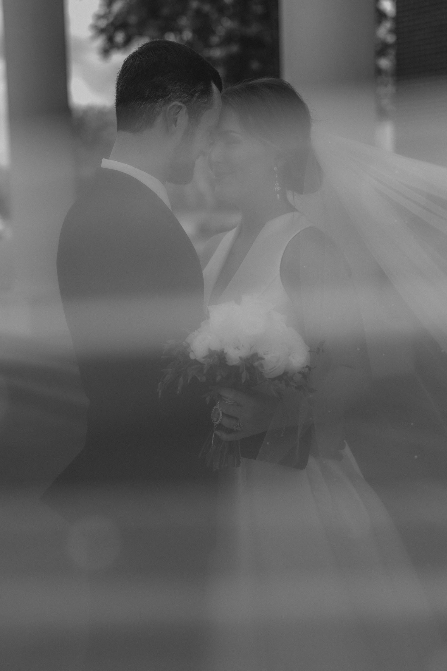 Romantic silhouettes of a wedding party gathered outdoors in soft focus black and white.