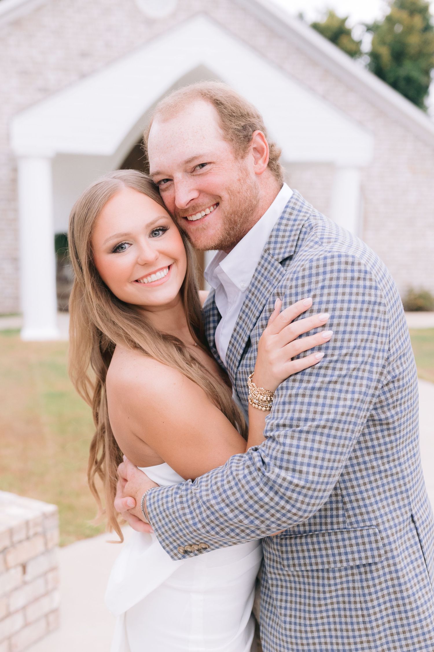 A romantic outdoor engagement photo shoot featuring a couple embracing and smiling in casual attire.