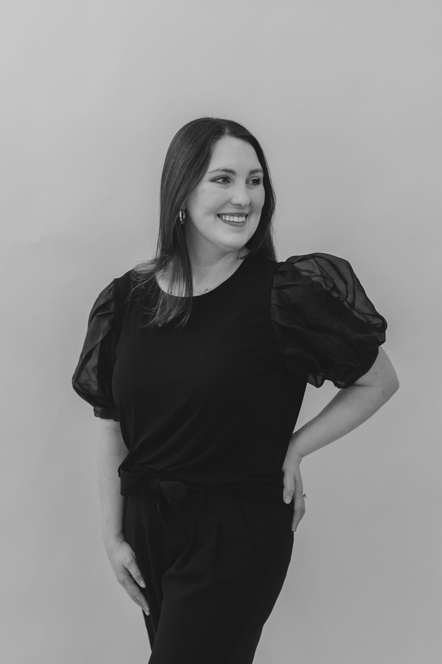 Woman in black puff sleeve dress posing against grey background in various dynamic poses.
