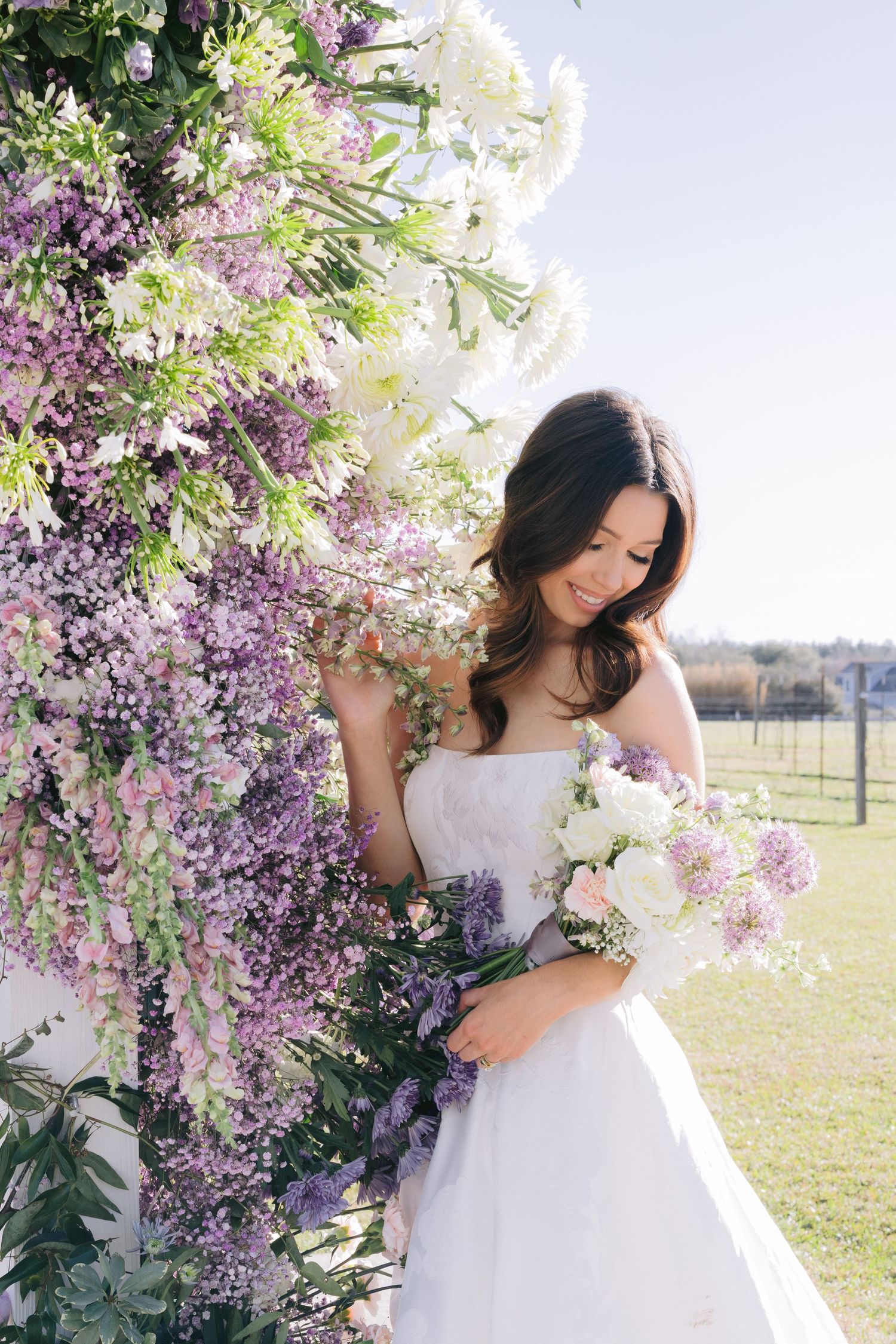 Ethereal bridal portrait among blooming purple and white flowers in an outdoor garden setting.