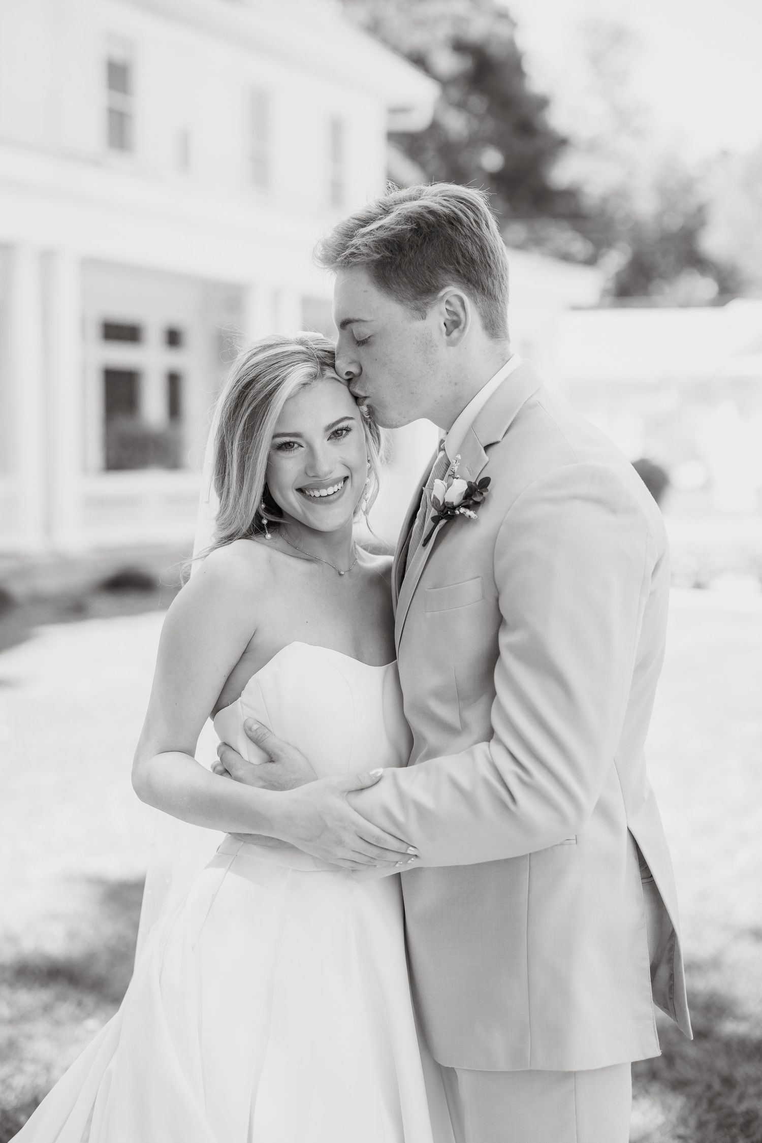 A romantic black and white portrait series of a couple sharing tender moments in wedding attire.