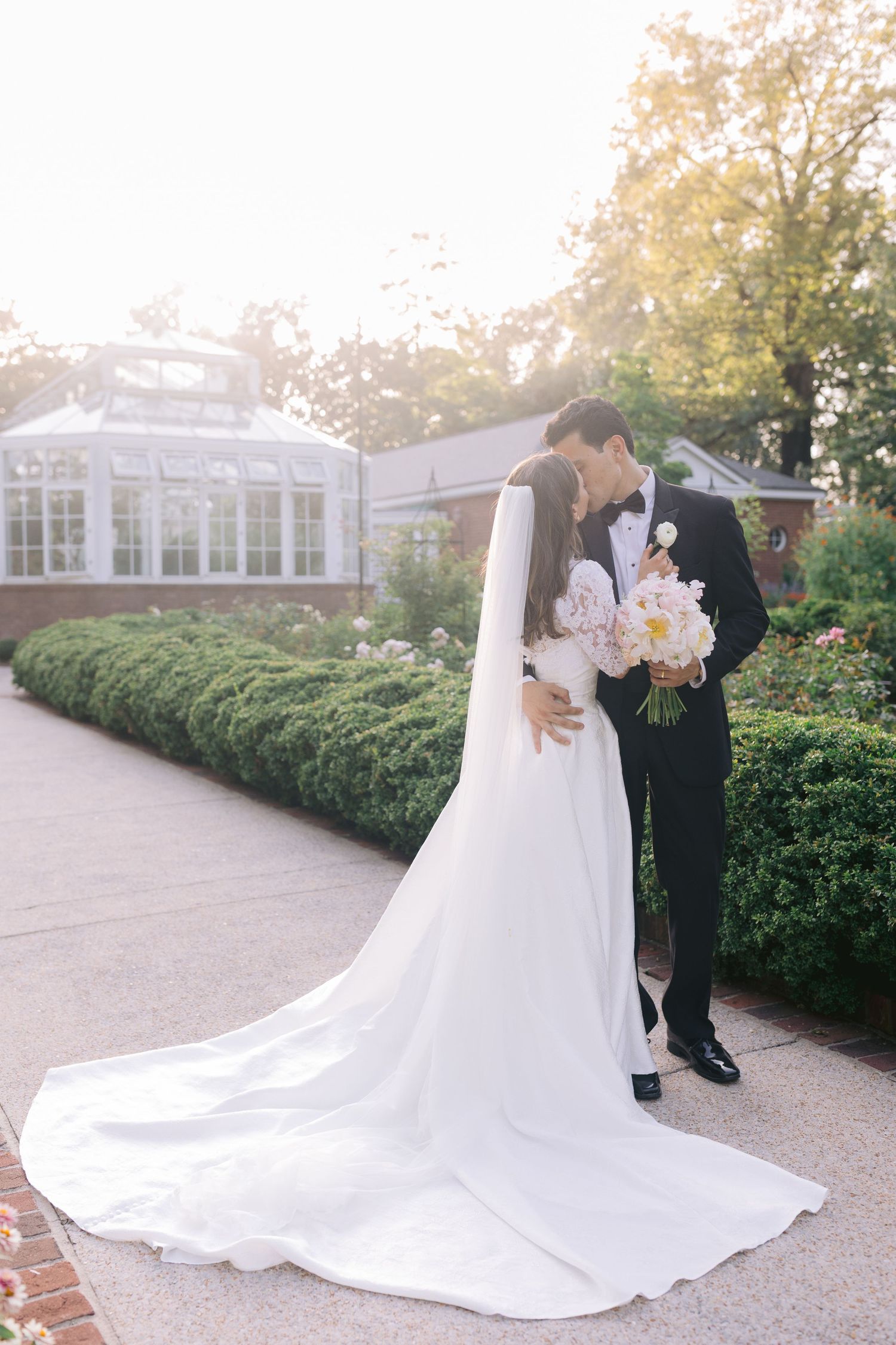 Sweeping white wedding dress train creates elegant lines against stone pathway during outdoor portraits.