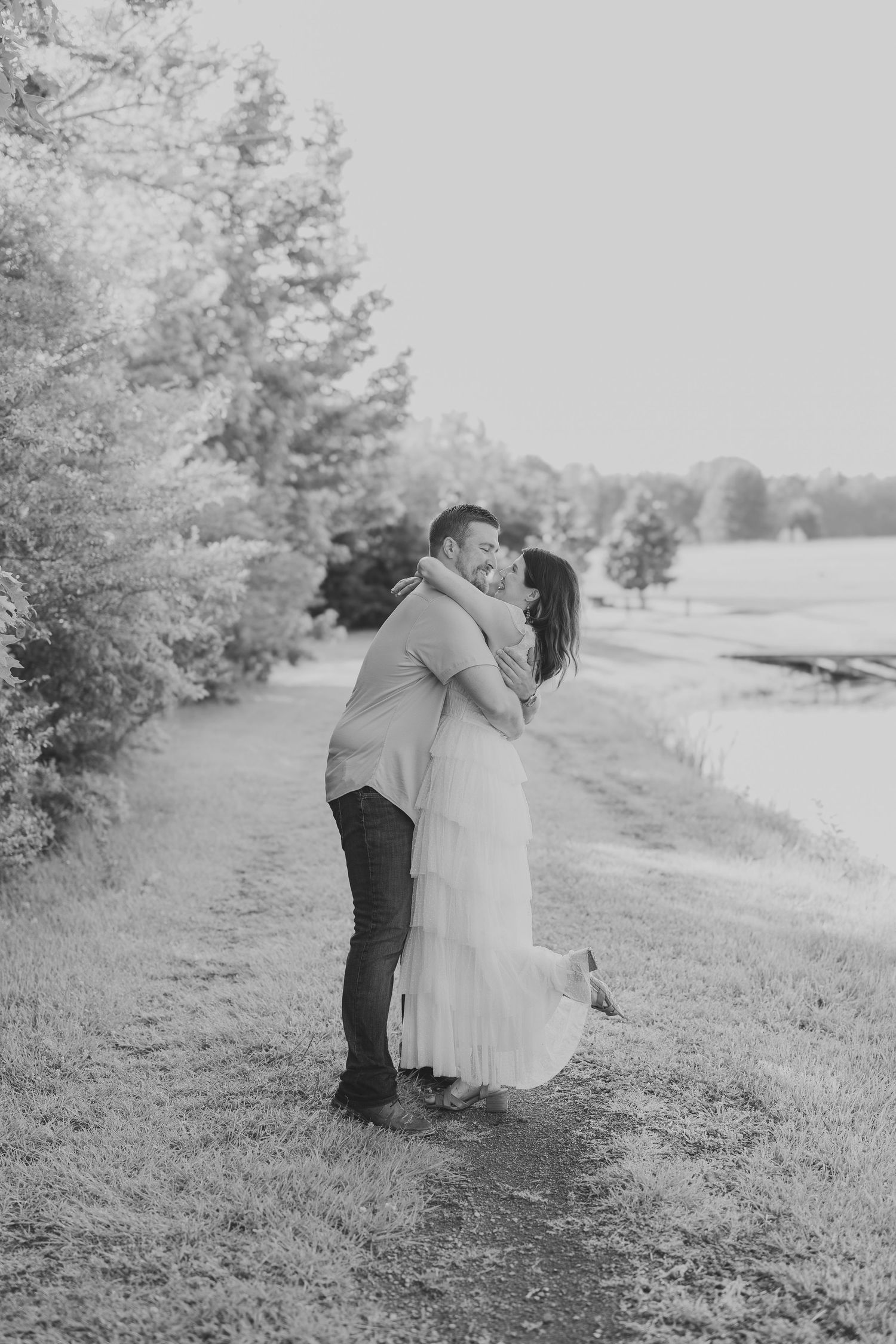 A couple shares tender embraces on a grassy hillside in a series of black and white photographs.