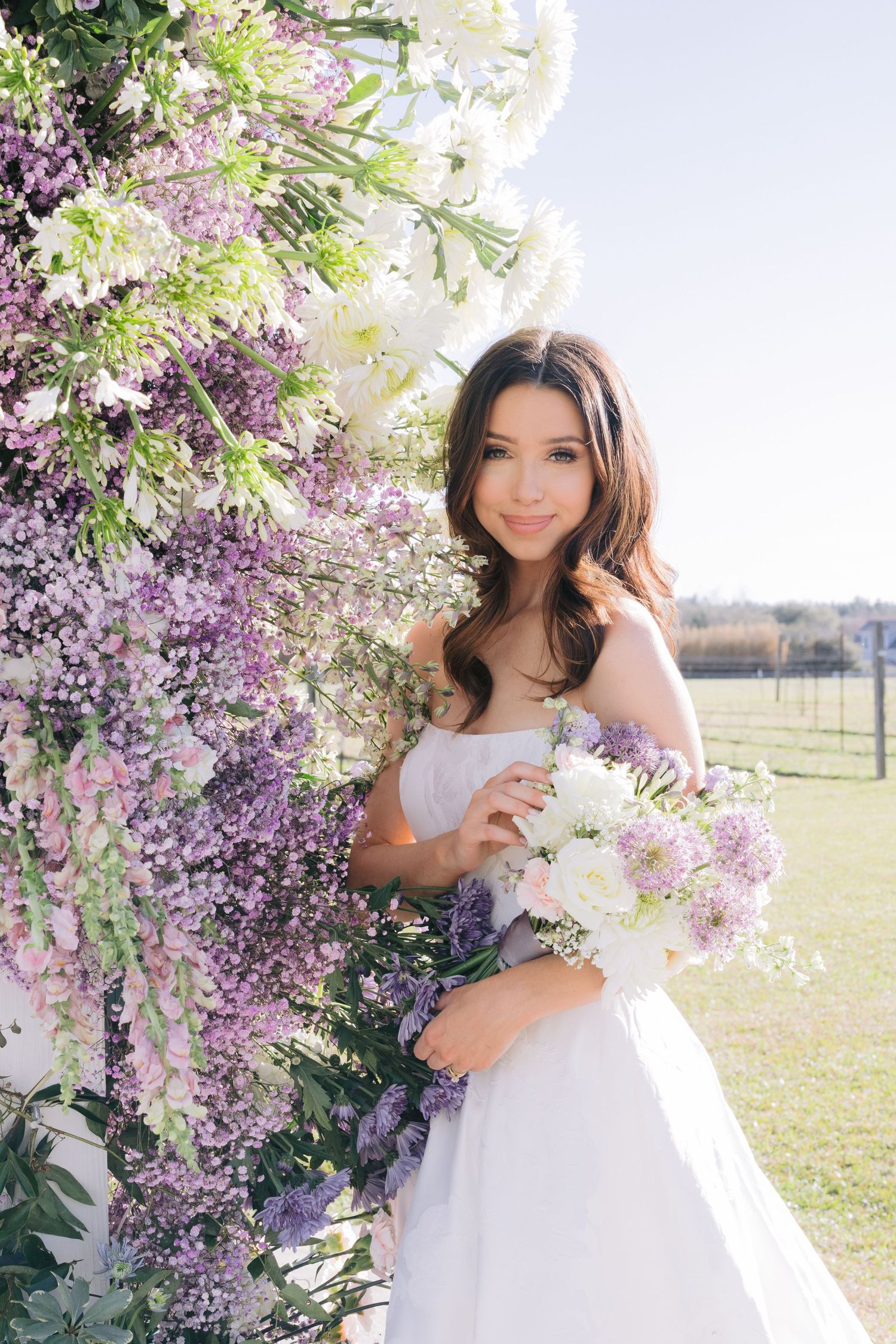 Beautiful wedding photos of bride taken in white dress against a backdrop of purple wisteria flowers and natural sunlight.