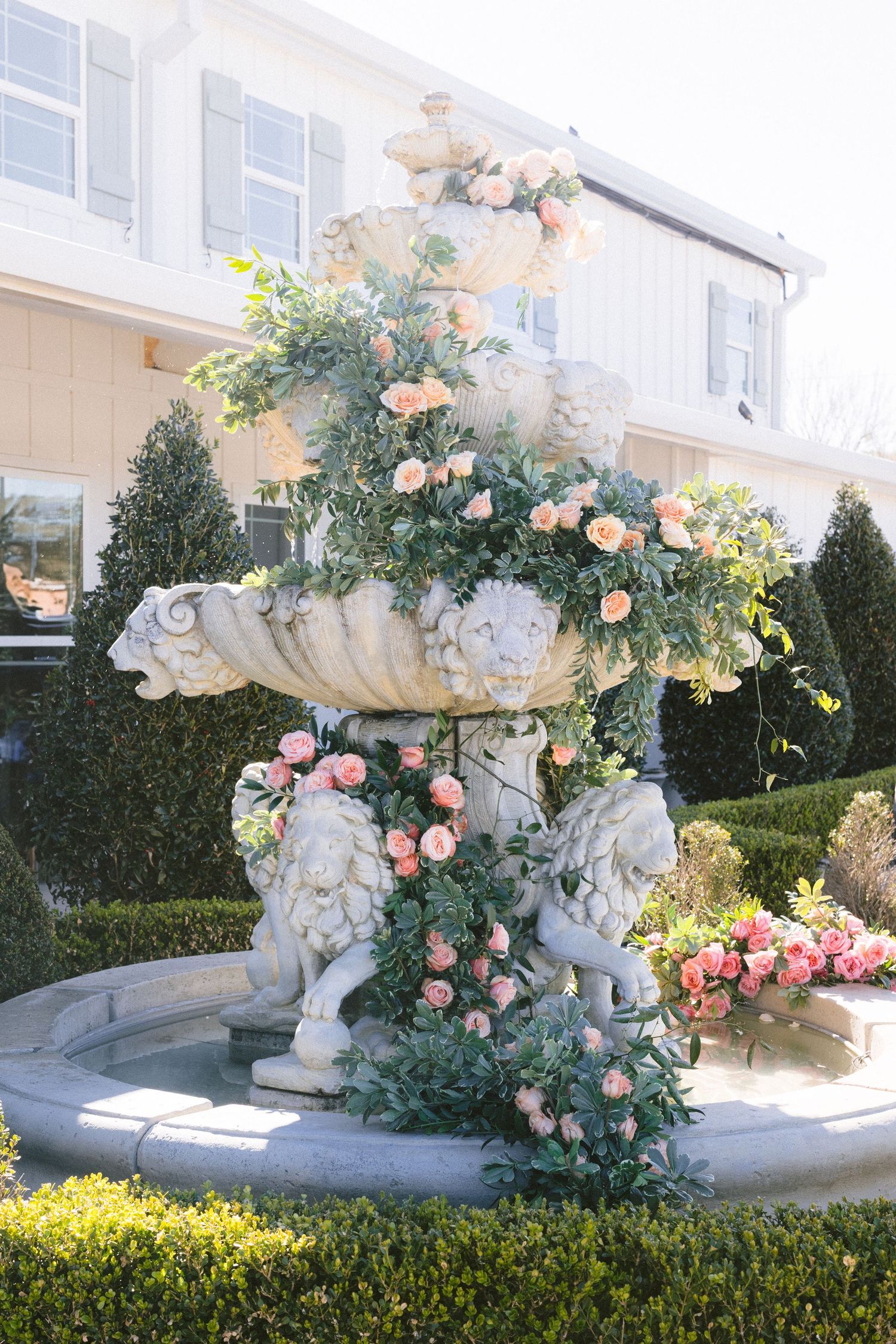 An elegant outdoor wedding arch decorated with pink roses and white flowers against a garden backdrop.