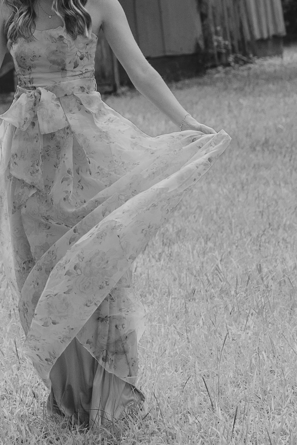 A flowing floral dress swirls gracefully in black and white as someone twirls in a grassy field.
