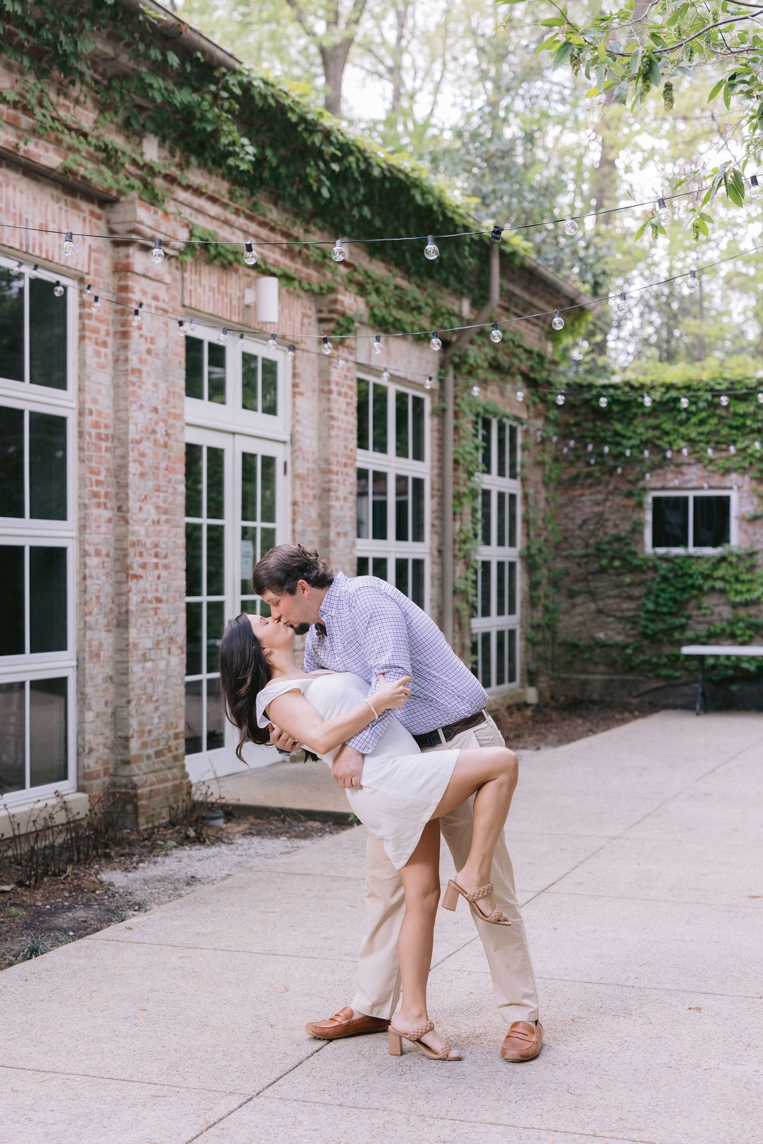 A romantic dip pose sequence captured against a brick building with ivy and white windows.