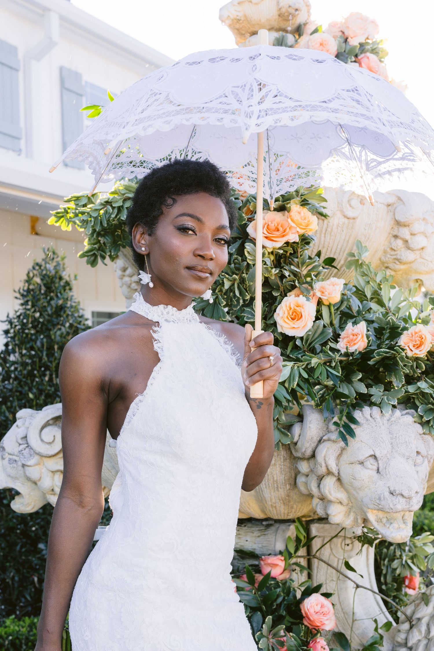 White lace parasol adorned with peach roses and greenery creates an elegant bridal backdrop.