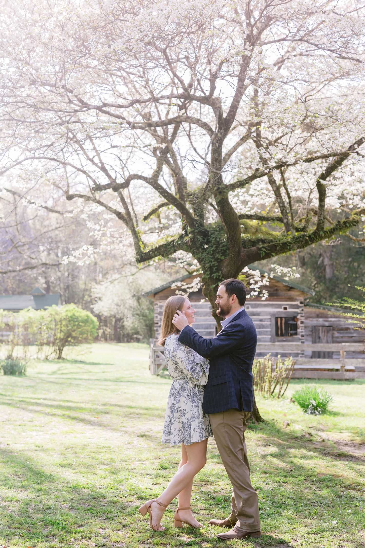 Romantic couple dancing under blooming cherry blossom trees in a springtime park setting.