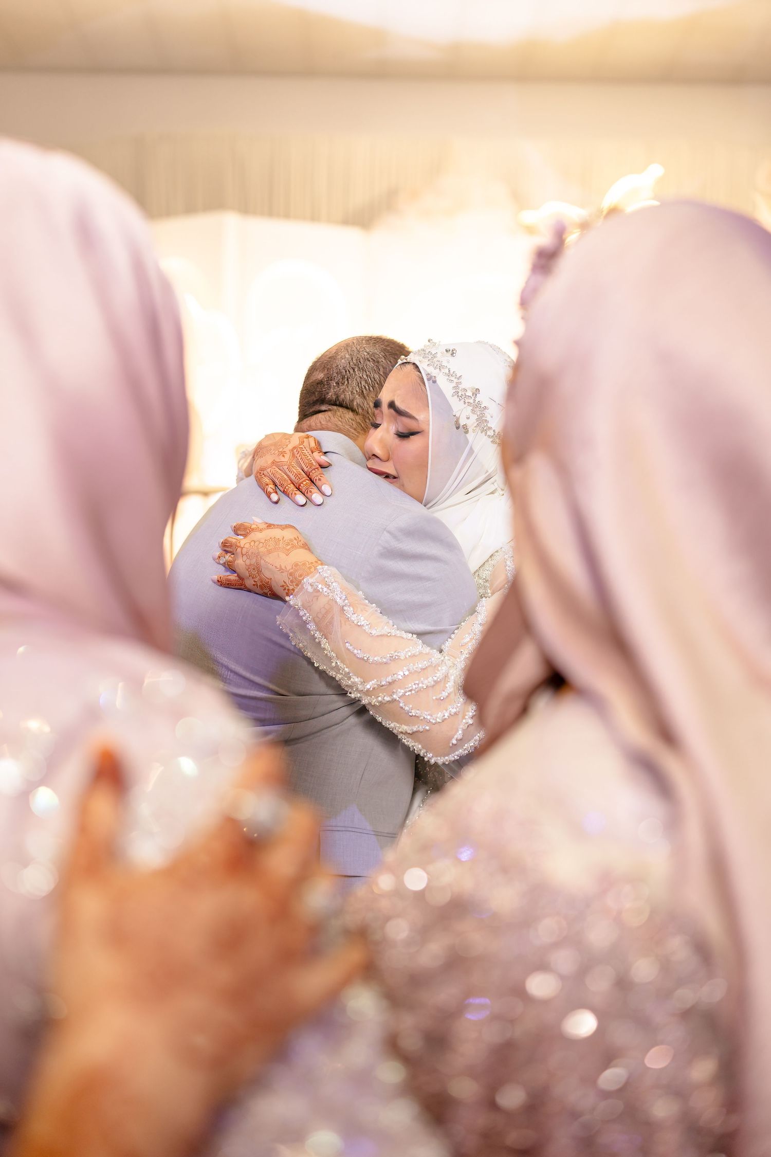 Two people in traditional wedding attire share an intimate embrace at a formal celebration.