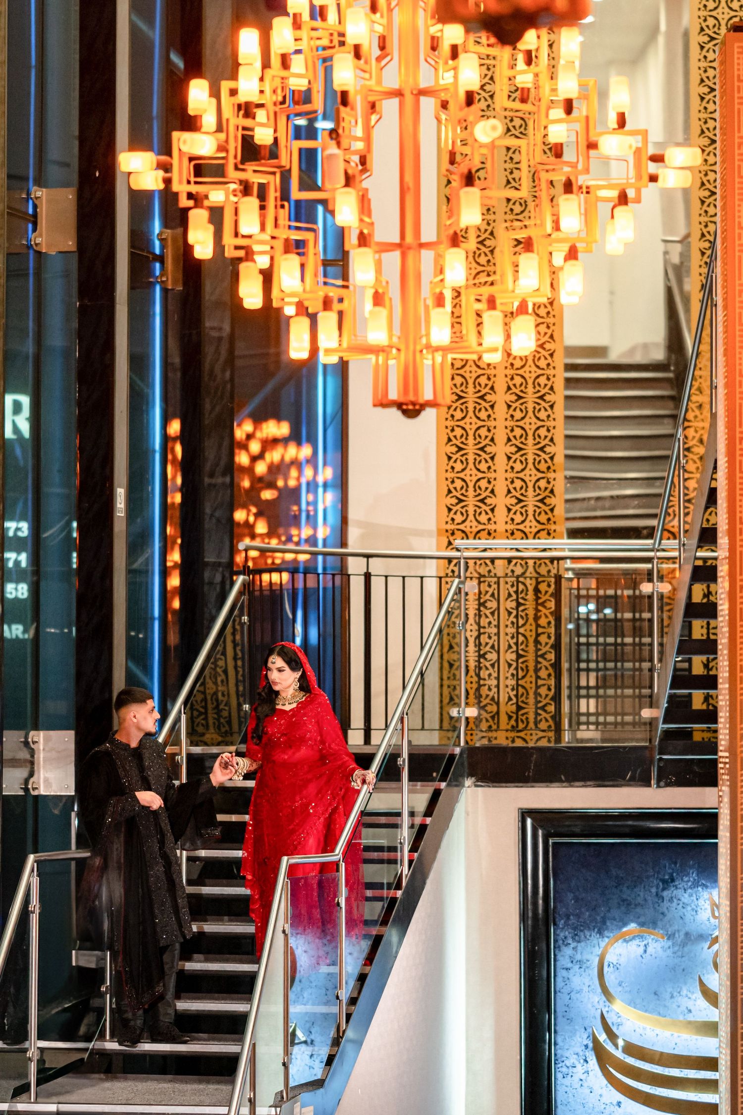 Decorative lantern installation illuminates a modern staircase with ornate patterns and gold accents in an elegant space.