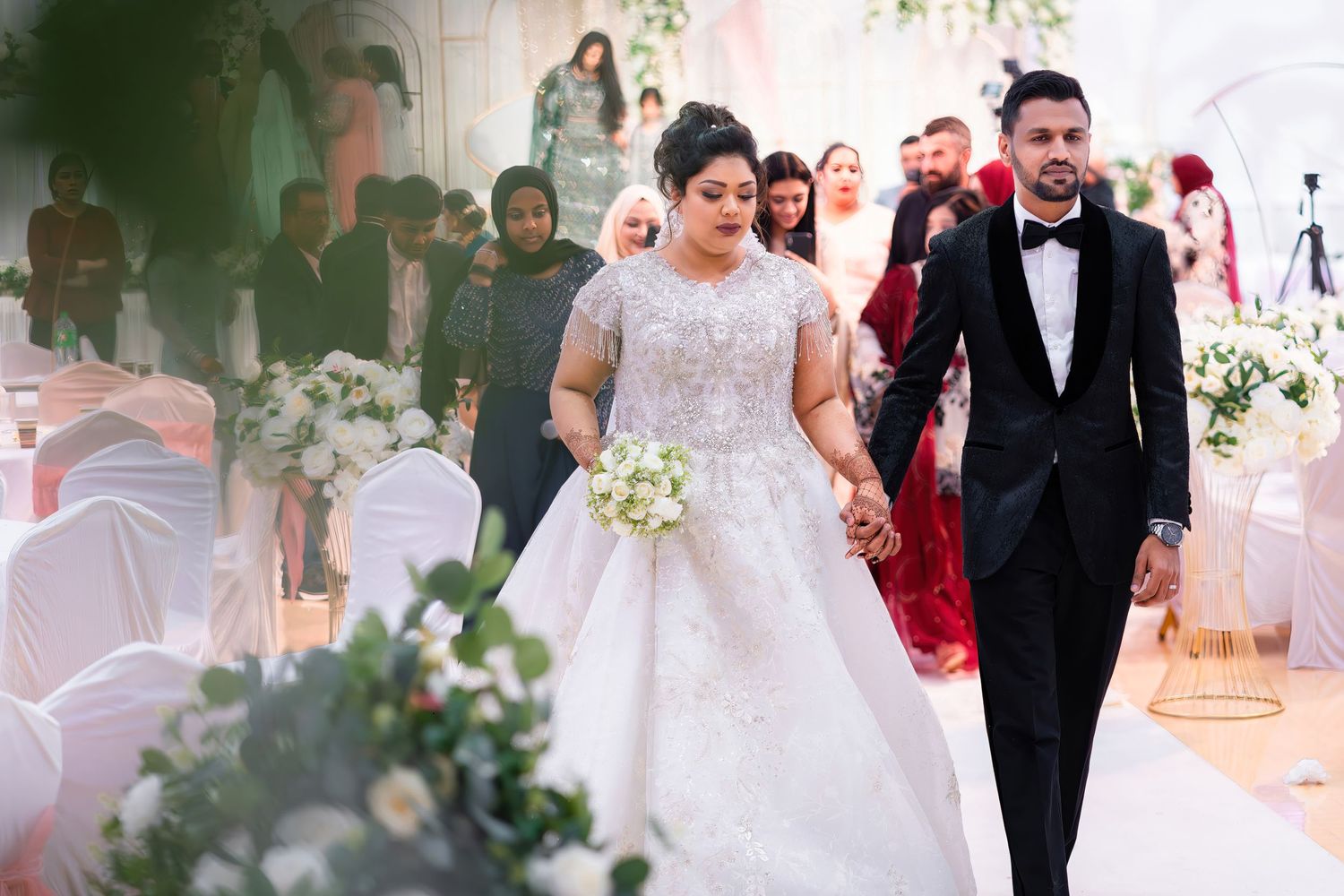 Leicester wedding photography couple outdoor ceremony. Newlyweds walk down the aisle at an elegant wedding ceremony with floral decorations.