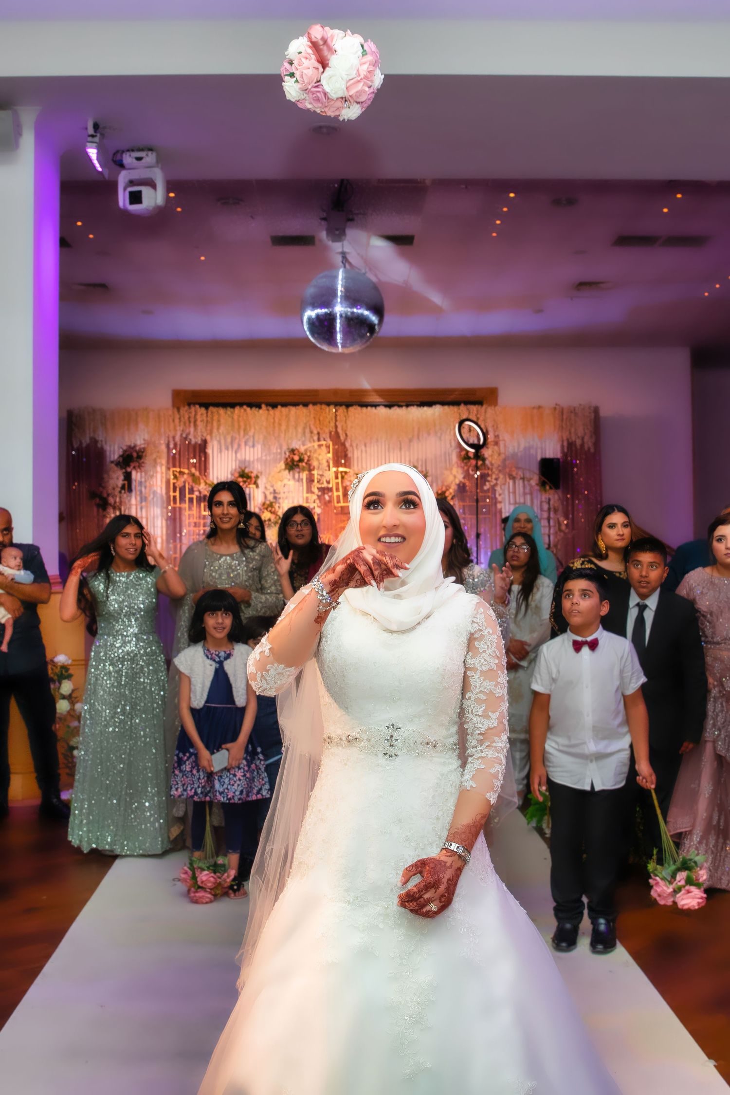 A bride in a white lace wedding dress performs during a reception celebration.