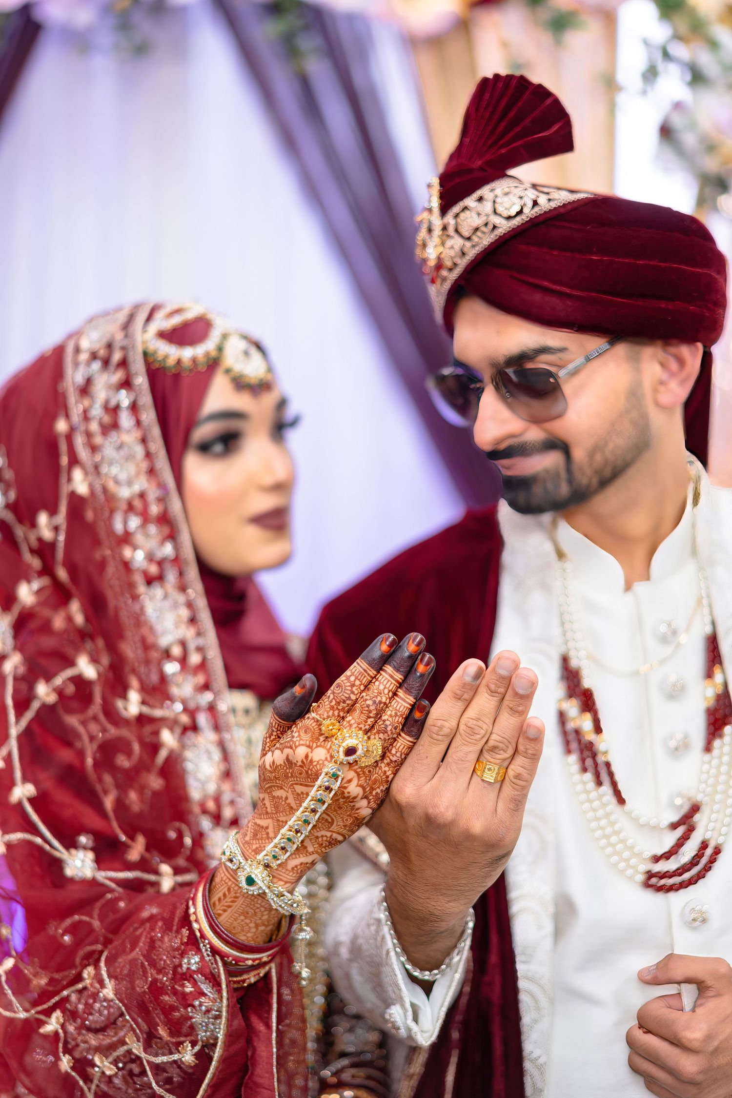 A couple in traditional wedding attire showing intricate henna designs during their ceremony.